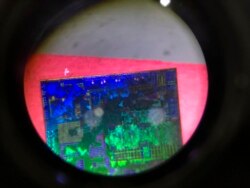 FILE - A Chinese microchip is seen through a microscope set up at the booth for the state-controlled Tsinghua Unigroup project which is driving China's semiconductor ambitions during the 21st China Beijing International High-tech Expo in Beijing.