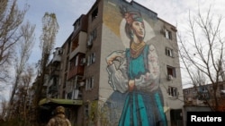 Ukrajinski vojnici pored stambene zgrade teško oštećene stalnim ruskim vojnim napadima u gradu Avdiivka na liniji fronta