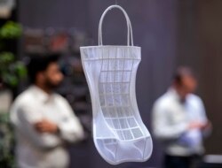 Pengunjung berdiri di belakang karya seni cetak 3d 'Morphables' karya Cathryn McAnespy di pameran internasional FabCon 3.D dan Rapid.Tech di Messe Erfurt di Erfurt, Jerman, Selasa, 25 Juni 2019. (Foto: AP/Jens Meyer )