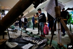 In this Friday, Feb. 1, 2019 photo, a flag of the Islamic State group and some of the weapons they used in battle, are on display in the Popular Mobilization Forces War Museum on al-Mutanabi Street, Baghdad, Iraq. (AP Photo/Khalid Mohammed)