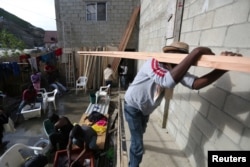 FILE - A Haitian migrant carries wood to build a house in a neighborhood of Tijuana, Baja California, that's known locally as Haitian Villa, Feb. 25, 2017.