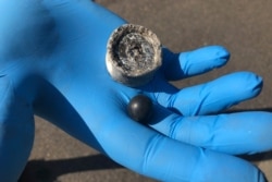 Activist Juniper Simonis holds two crowd control agents that Simonis found on the street by storm drains near the Immigration and Customs Enforcement building, where numerous protests have been held in Portland, Ore., on Oct. 2, 2020.