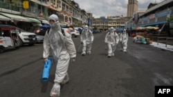 រូបឯកសារ៖ ក្រុមការងារដែលស្ថិតក្នុងសម្លៀកបំពាក់ការពារខ្លួនពីជំងឺ​កូវីដ១៩ កំពុងត្រៀមបាញ់ថ្នាំសម្លាប់មេរោគនៅផ្សារអូរឬស្សី បន្ទាប់ពីមានករណីឆ្លងក្នុងចំណោមអាជីវករនៅផ្សារនេះ នៅរាជធានីភ្នំពេញ កាលពីថ្ងៃទី ៤ ខែមេសា ឆ្នាំ ២០២១។