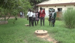 Nkosilathi Nyathi, center, talks with the "Ozone Defenders Club" at Chemabondo Primary School about a biogas station he helped create in 2016 that is used to prepare food for students, in Victoria Falls, Feb. 26, 2020. (Columbus Mavhunga/VOA)