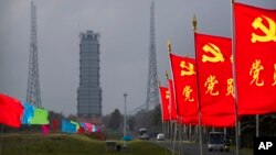 FILE - Flags with the logo of the Communist Party of China fly in the breeze near a launch pad at the Wenchang Space Launch Site in Wenchang in southern China's Hainan province, Monday, Nov. 23, 2020. China’s military has expanded a navy base in the South China Sea.