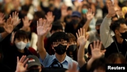 FILE - Protesters wearing face masks hold up their hands during an anti-government protest at Yoho Mall in Yuen Long, Hong Kong, Nov. 21, 2019.