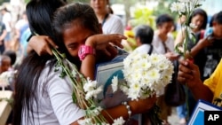 FILE - Relatives of victims in President Rodrigo Duterte's so-called war on drugs comfort each other as they gather at a Roman Catholic church in suburban Quezon city, March 15, 2019, northeast of Manila, Philippines.