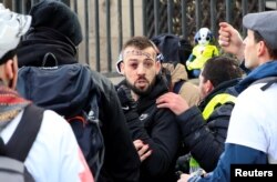 An injured protester is given help during a demonstration by the "yellow vest" movement in Paris, Feb. 9, 2019.