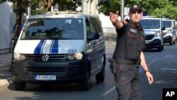 Policajac u Podgorici usmerava kolonu policijskih vozila koja prevoze osumnjilčene za državni udar u oktobru 2016. (Foto: AP/Risto Božović)