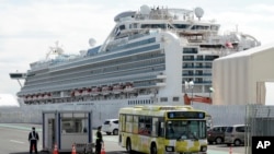 រថយន្តដឹកអ្នកដំណើរចេញពីនាវា Diamond Princess ពីកំពង់ផែនៅក្រុងយូកូហាម៉ា ប្រទេសជប៉ុន កាលពីថ្ងៃពុធ ទី១៩ ខែកុម្ភៈ ឆ្នាំ២០២០។ 