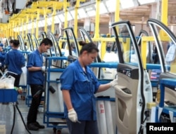 FILE - Employees work at a production line inside a factory of Saic GM Wuling, in Liuzhou, Guangxi Zhuang Autonomous Region, China, June 19, 2016.
