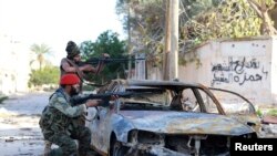 Pasukan pro-pemerintah Libya membidik senjata mereka dalam bentrokan dengan Dewan Shura Revolusioner Libya, aliansi man tan pemberontak anti-Gadhafi, yang bergabung dengan kelompok Islamis Ansar al-Sharia, di Benghazi, 28 Desember 2014.