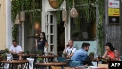 A waitress wearing a protective face mask and plastic gloves serves coffee at a cafe in central Athens, May 25, 2020.