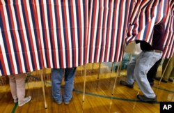 FILE - A voter enters a booth at a polling place in Exeter, N.H., Nov. 8, 2016. Donald Trump won the presidency, even as he lost the popular vote to Democrat Hillary Clinton. He nonetheless tweeted on Nov. 26 that he won the popular vote. and alleged there was “serious voter fraud” in California, New Hampshire and Virginia. There’s no evidence to back up those claims.