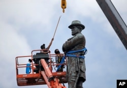 FILE - Workers prepare to take down the statue of former Confederate general Robert E. Lee, which stands more than 100 feet tall, in Lee Circle in New Orleans, May 19, 2017.