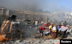 Civilians prepare to carry the dead body of an unidentified man from the scene of an explosion in KM4 street in the Hodan district of Mogadishu, Oct. 14, 2017.