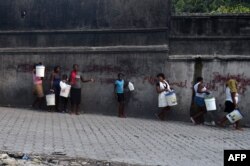 A group of women and children walk to buy water in the neighborhood of Petion Ville, in the Haitian Capital Port-au-Prince, on Feb. 14, 2019.