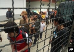 泰国宋卡省的维吾尔穆斯林在一辆警车旁排队。