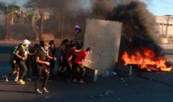 FILE - Anti-government protesters set fires and close a street during a demonstration in Baghdad, Oct. 4, 2019.