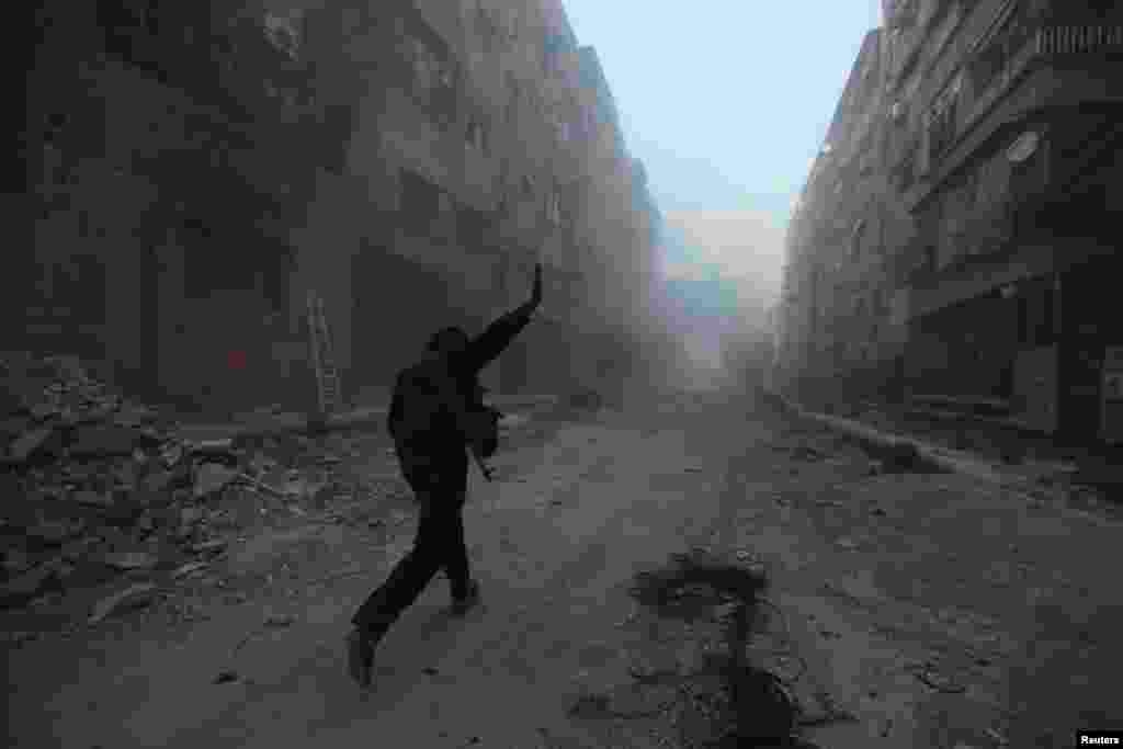 A rebel fighter gestures as he runs across a street in Mleha suburb of Damascus, April 2, 2014. 