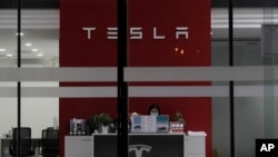 Seorang resepsionis tampak bekerja di showroom Tesla di Beijing, China, pada 4 Januari 2022. (Foto: AP/Ng Han Guan)