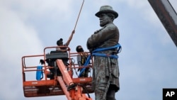 FILE - Workers prepare to take down the statue of former Confederate general Robert E. Lee in New Orleans, May 19, 2017.