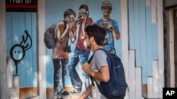 Seorang pria mengenakan masker saat berjalan di jalan utama di Tel Aviv, Israel, 15 Maret 2020.