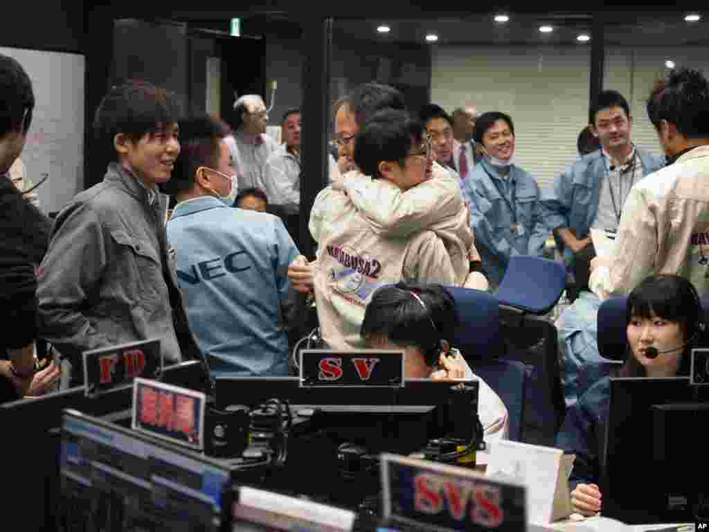 In this photo provided by the Japan Aerospace Exploration Agency, staff of the Hayabusa2 Project react as they confirm Hayabusa2 made a maneuver at the control room of the JAXA Institute of Space and Astronautical Science in Sagamihara, near Tokyo, Feb. 2