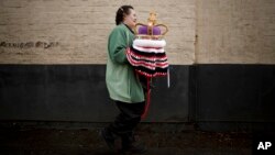 Janette Vorster of the 'Hurst Hookers' knitting group carries a crocheted crown made as a post box topper during a pre-coronation 'yarn bombing' in the village of Hurst, near Reading, England, April 21, 2023.