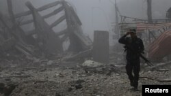 FILE - A member of the Iraqi Federal Police walks by destroyed buildings from clashes in the Old City of Mosul, Iraq, July 10, 2017. 