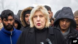 FILE - Surrounded by migrants, Dunja Mijatovic, the Council of Europe commissioner for human rights, addresses reporters at the Vucjak refugee camp outside Bihac, northwestern Bosnia, Dec. 3, 2019.