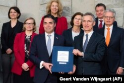 BELGIUM -- NATO Secretary-General Jens Stoltenberg, 3rd right, and Macedonian Foreign Minister Nikola Dimitrov, 3rd left, pose for photographers together with NATO permanent representatives after they signed the "accession protocol" in a ceremony at NATO