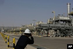Seorang fotografer memotret ladang minyak Khurais, 150 km timur-timur laut Riyadh, Arab Saudi, 28 Juni 2021. (Foto: AP)