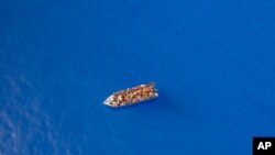Un groupe dont on pense qu'il s'agit de migrants originaires de Tunisie à bord d'un bateau en bois précaire, à environ 20 miles au sud-ouest de l'île italienne de Lampedusa.