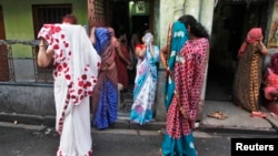 FILE - Indian sex workers cover their faces as they react to the camera while watching a week-long sex workers' freedom festival at the Sonagachi red-light area in Kolkata July 24, 2012.