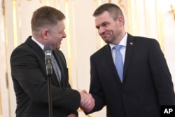 FILE - Outgoing Slovakian Prime Minister Robert Fico, left, shakes hands with Peter Pellegrini, who will replace Fico as prime minister, at the Presidential palace in Bratislava, March 15, 2018.
