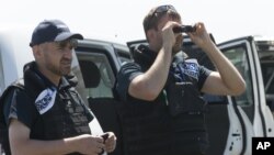 Members of OSCE mission to Ukraine examine the area of the Malaysia Airlines Flight 17 plane crash near the village of Hrabove, Donetsk region, eastern Ukraine Friday, Aug. 1, 2014.
