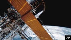 FILE - In this photograph provided by NASA, most of the giant Hubble Space Telescope can be seen as it is suspended in space by the shuttle Discovery's Remote Manipulator System following the deployment of part of its solar panels and antennae, April 25, 