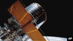 FILE - In this photo provided by NASA, most of the Hubble Space Telescope can be seen as it is suspended in space by the shuttle Discovery's Remote Manipulator System following the deployment of part of its solar panels and antennae, April 25, 1990.