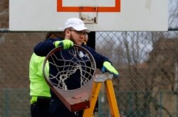 A Pittsburgh Public Works employee removes a basketball rim from a city court in an effort to encourage social distancing, March 30, 2020.