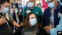 Bianca Jimenez, center, is offered a prayer by a spiritual care worker alongside her mother and her father, while being cheered by hospital staff as the 600th COVID-19 patient discharged from hospital care, April 24, 2020.