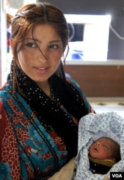 A young mother, displaced from Aleppo, cares for her newborn at a government center in Dummar, Syria. (E. Arrott/VOA)