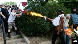 A counter demonstrator uses a lighted spray can against a white nationalist demonstrator at the entrance to Lee Park in Charlottesville, Va., Aug. 12, 2017.