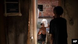 People carry food donated by the Rio de Paz NGO to be distributed to residents of the Mandela slum amid the COVID-19 pandemic in Rio de Janeiro, Brazil, March 27, 2021.