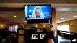 File - Waitress Lauren Musial watches a television briefing by Pennsylvania Health Secretary, Dr. Rachel Levine, at the Penrose Diner, Nov. 17, 2020, in South Philadelphia that plans to prohibit indoor dining at restaurants, shutter casinos, gyms