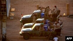 FILE - Members of Sudan's intelligence services shoot bullets in the air at the headquarters of the Directorate of General Intelligence Service, in the Riyadh district of the capital Khartoum, Jan. 14, 2020. 