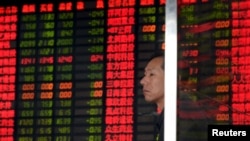 Seorang investor berdiri di depan papan monitor yang menunjukkan harga-harga saham di Shanghai, China (2/9). Bursa-bursa saham domestik China telah anjlok hampir 40 persen sejak pertengahan Juni.