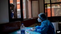 Seorang petugas kesehatan mencatat nama seseorang sebelum ia dites Covid-19 di New Delhi, India, Kamis, 8 Oktober 2020. India adalah negara kedua yang paling banyak terkena virus Ccorona di dunia setelah Amerika Serikat. (Foto: AP/Altaf Qadri)