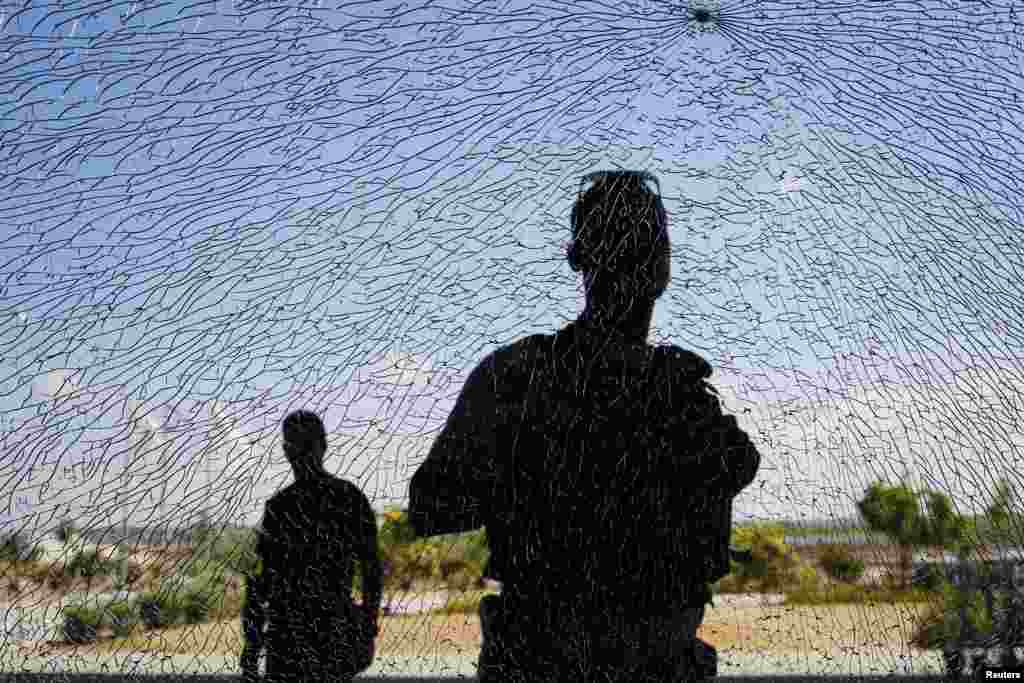 Anggota keamanan Israel mengamati jendela yang rusak akibat serpihan bom setelah roket jarak pendek mendarat dekat Erez Crossing, terminal pejalan kaki/kargo di perbatasan Jalur Gaza Israel, 16 Juli 2014.