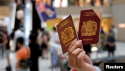 Seorang demonstran pro-demokrasi memegang paspor British National Overseas (BNO) saat berlangsungnya aksi protes menentang UU Keamanan Nasional baru di Hong Kong, 1 Juni 2020. (REUTERS / Tyrone Siu)